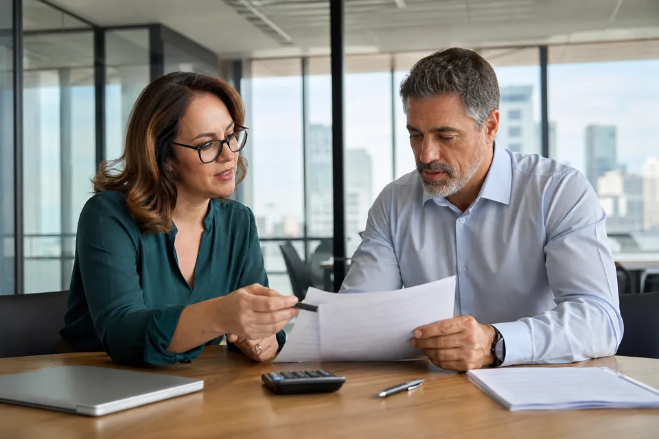 Finance and IT leads reviewing a printed license renewal quote at a conference table with a laptop open